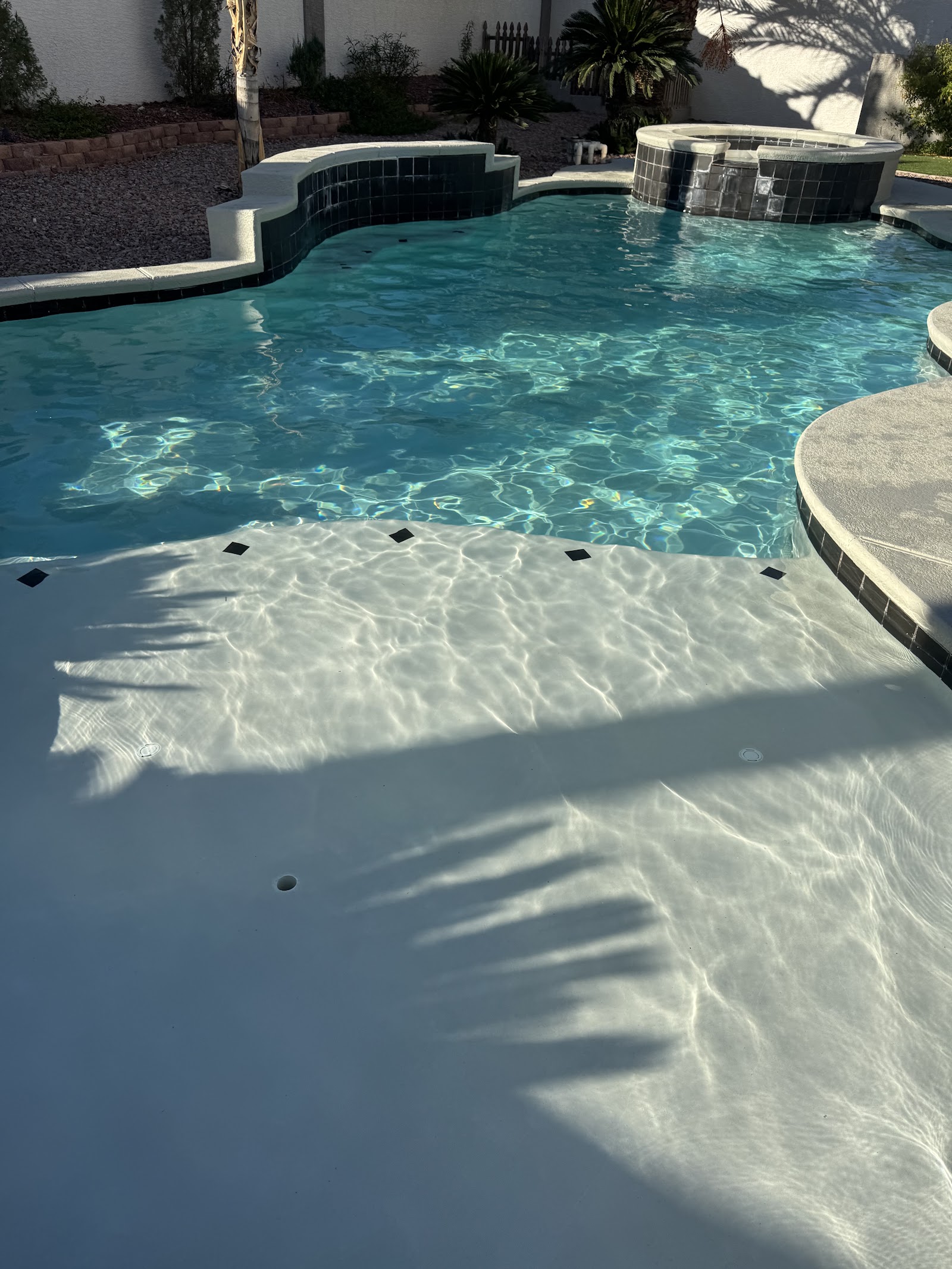 Clean backyard pool and spa with clear blue water and tiled steps
